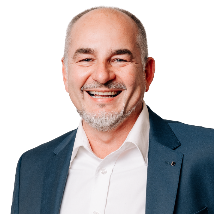 Kandidat Siggi Scheder im Halbprofil, in blauem Jacket und weißem Hemd gekleidet, freundlicher Ausdruck, vor neutralem Hintergrund.